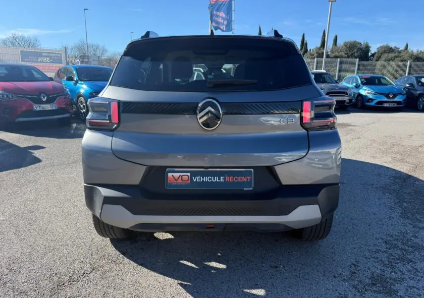 Vue arrière d'une Citroën C3 gris 2025 avec feux arrière LED et barres de toit visibles sur parking.