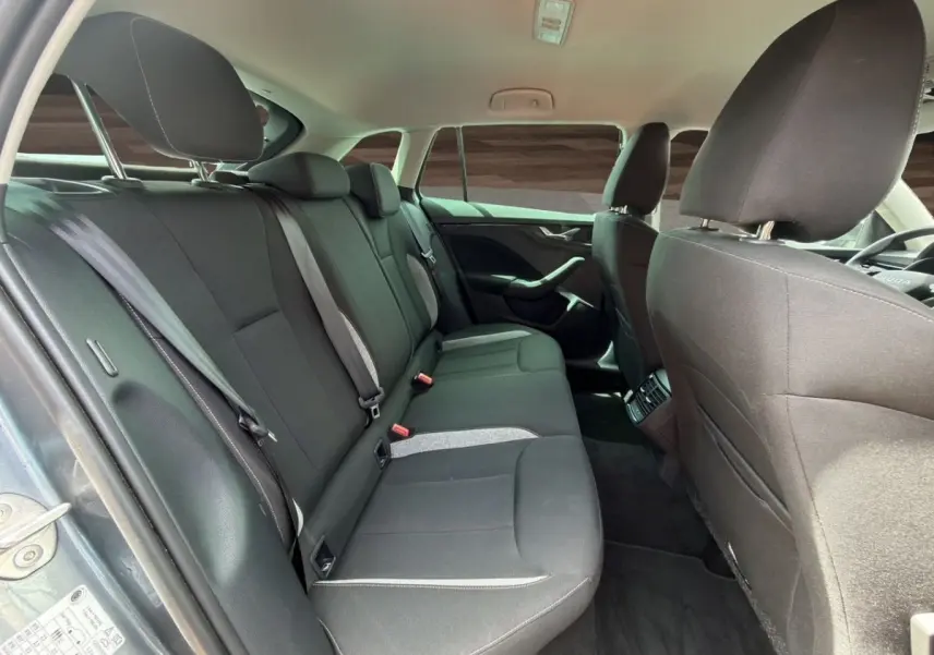 Vue intérieure arrière de la Skoda Scala gris foncé, montrant la banquette et les sièges avant en tissu noir.