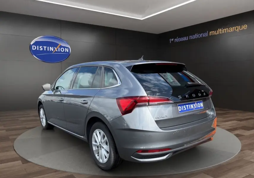 Vue 3/4 arrière droite d'une Skoda Scala gris foncé avec feux arrière LED et logo distinctif au showroom.