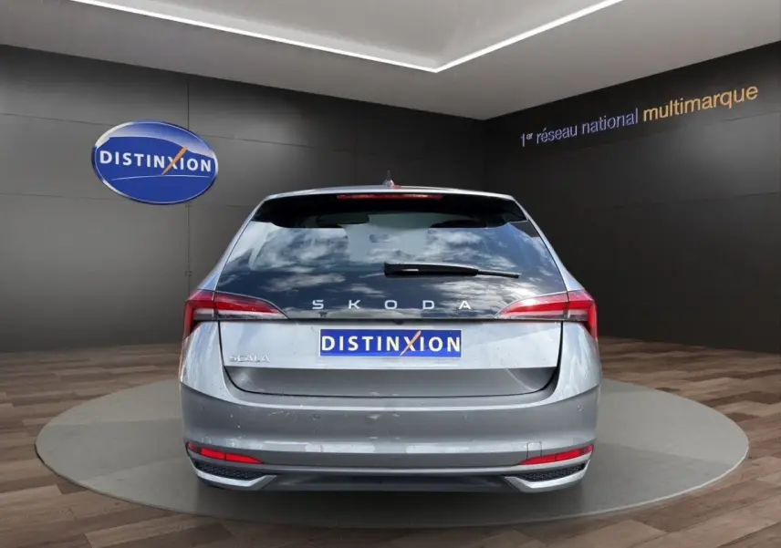 Vue arrière d'une Skoda Scala gris foncé, avec feux LED et logo distinctif sur fond de showroom.