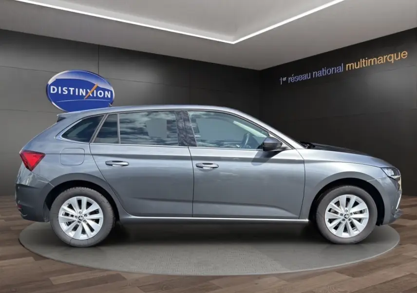 Vue de profil côté gauche d'une SKODA SCALA gris foncé 2025 dans un showroom avec jantes alliage et vitres teintées.