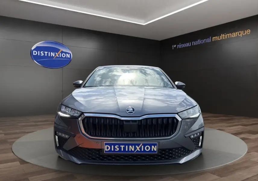 Vue frontale d'une Skoda Scala gris foncé avec calandre noire et phares LED allumés en showroom.