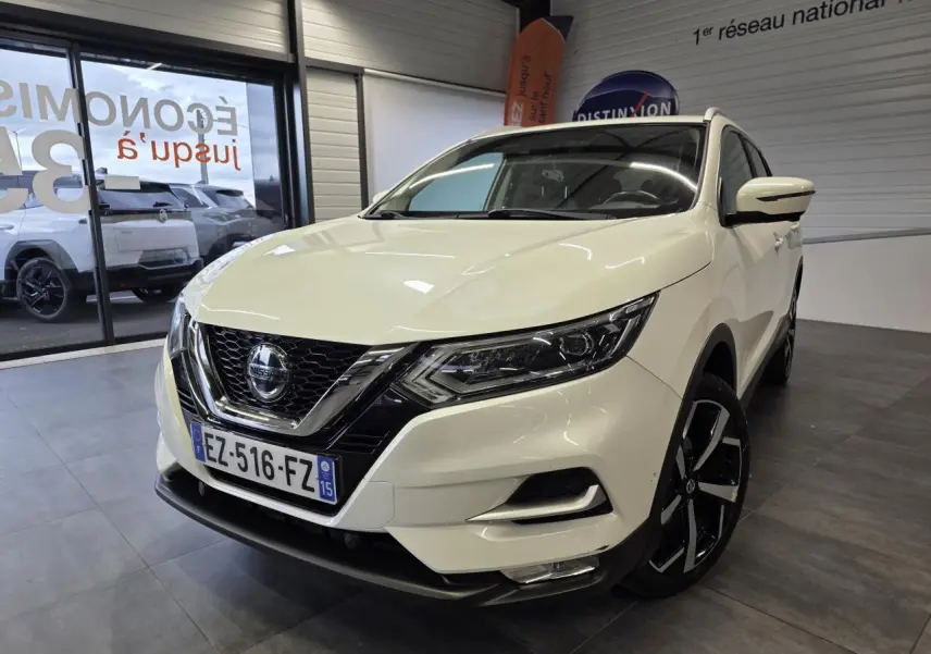 Nissan Qashqai blanc vue 3/4 avant droit en intérieur, avec jantes alliage noires et calandre chromée.