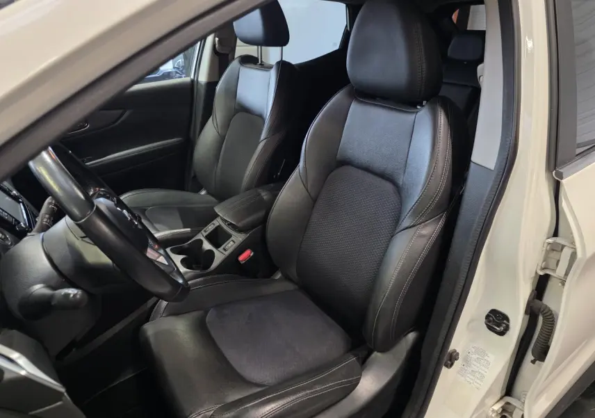 Vue intérieure côté conducteur du Nissan Qashqai blanc de 2018, sièges sport en cuir noir et accoudoir central.