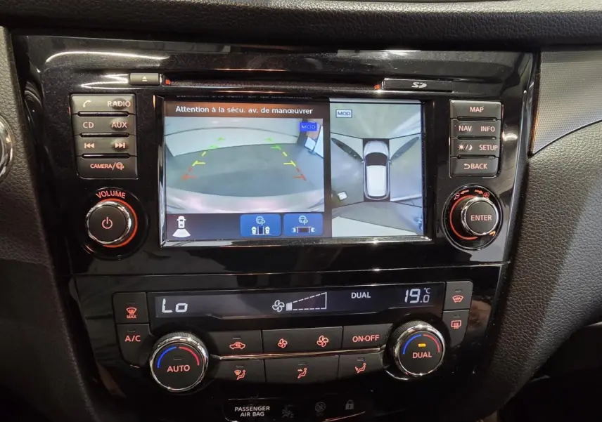 Vue rapprochée de la console centrale noire du Nissan Qashqai blanc avec écran de caméra 360° et commandes climatisation.
