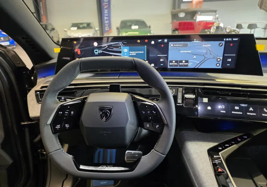 Vue intérieure centrée sur le volant compact du Peugeot 3008 gris titanium 2026 avec tableau de bord numérique large.