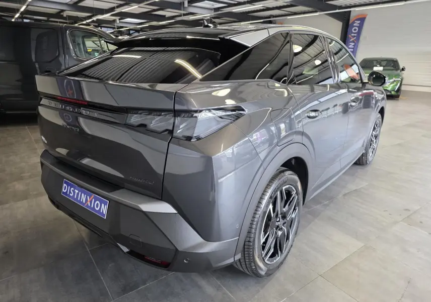 Vue 3/4 arrière droite du Peugeot 3008 gris titanium 2026, avec jantes noires et vitres teintées en showroom.