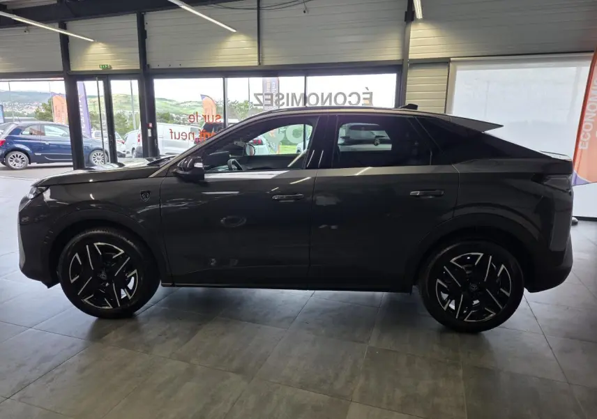 Vue de profil côté gauche d’un Peugeot 3008 gris titanium 2026 en version hybride GT Exclusive, en showroom.