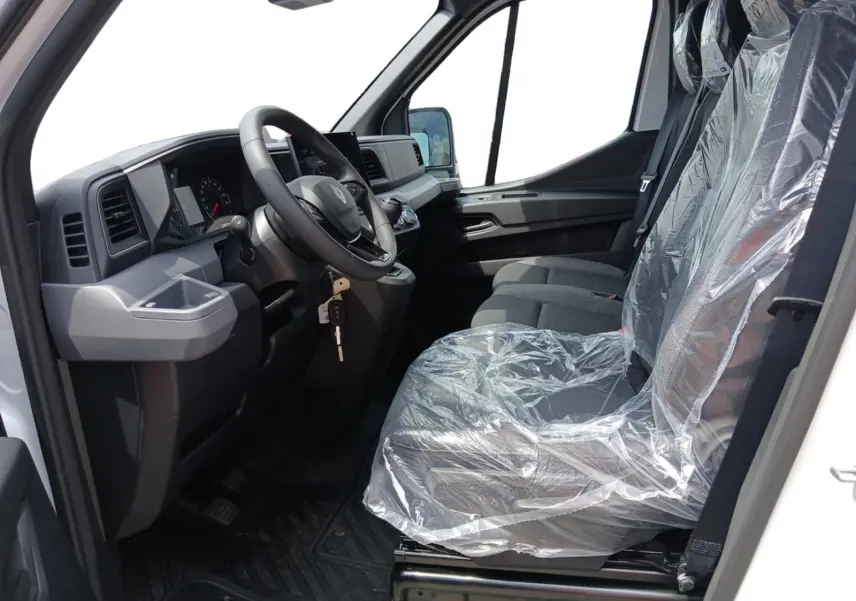 Vue intérieure côté conducteur du Renault Master blanc 2026, montrant le volant, tableau de bord et sièges protégés par film plastique.