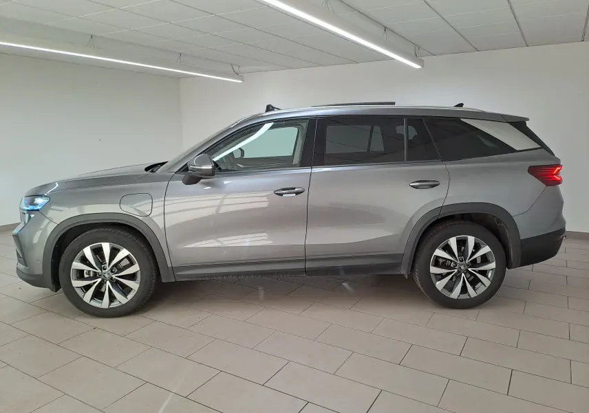 Vue de profil côté gauche d'un Skoda Kodiaq gris graphite hybride rechargeable avec jantes alliage 19 pouces dans un showroom.