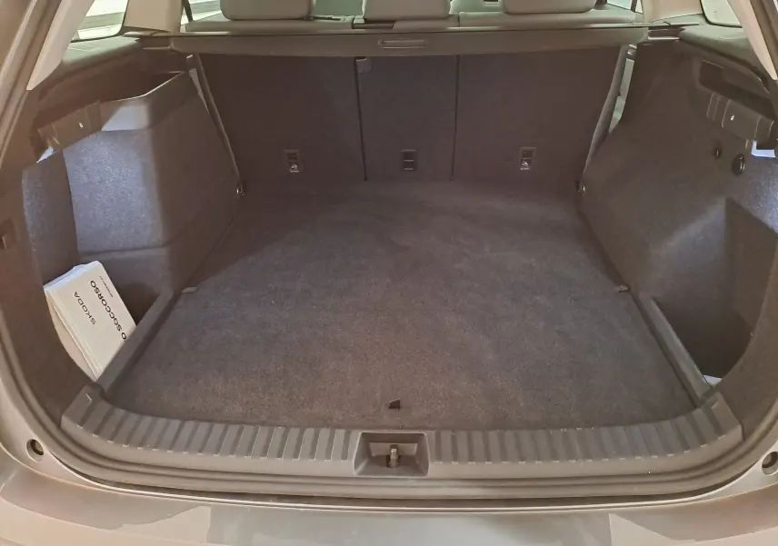 Coffre ouvert vu de l'arrière d'un Skoda Kodiaq gris graphite, montrant un espace de chargement propre et spacieux.