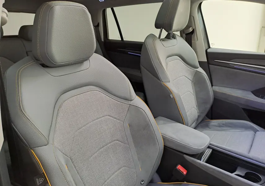 Vue intérieure rapprochée des sièges avant gris avec surpiqûres orange du Skoda Kodiaq 2025, côté droit visible.