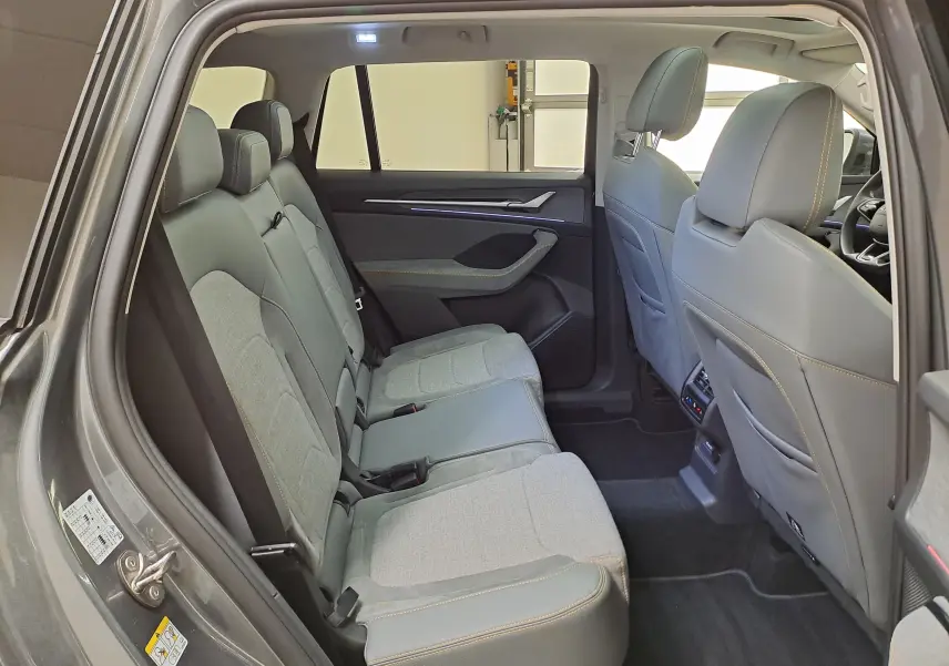 Vue intérieure côté gauche des sièges arrière du Skoda Kodiaq gris graphite avec sellerie mixte tissu et cuir et éclairage d'ambiance.