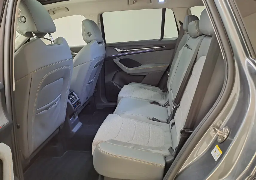 Vue intérieure côté droit des sièges arrière gris clair et cuir gris foncé du Skoda Kodiaq 2025 avec toit panoramique ouvert.