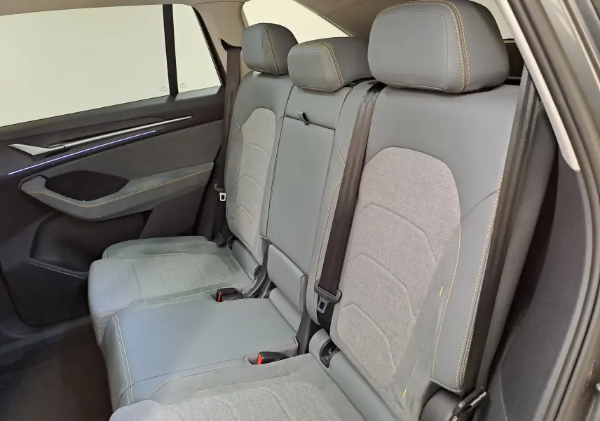 Vue côté droit des sièges arrière gris clair et foncé du Skoda Kodiaq 2025 avec surpiqûres jaunes et ceinture noire.