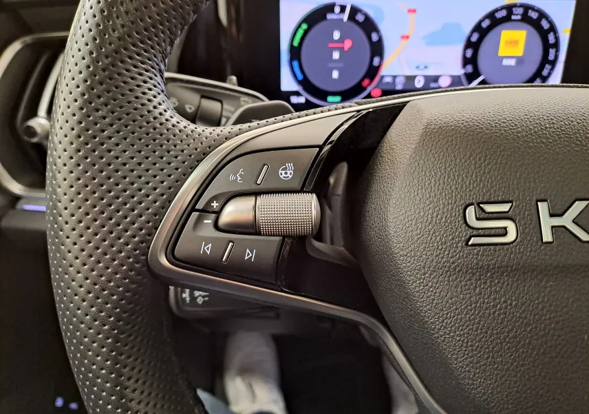 Gros plan sur le volant perforé gauche du Skoda Kodiaq gris graphite avec commandes multifonctions et tableau de bord numérique.