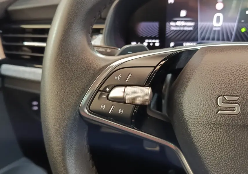Gros plan sur le volant cuir et alu de la Skoda Scala 2025 avec commandes multifonctions et affichage numérique flou en arrière-plan.