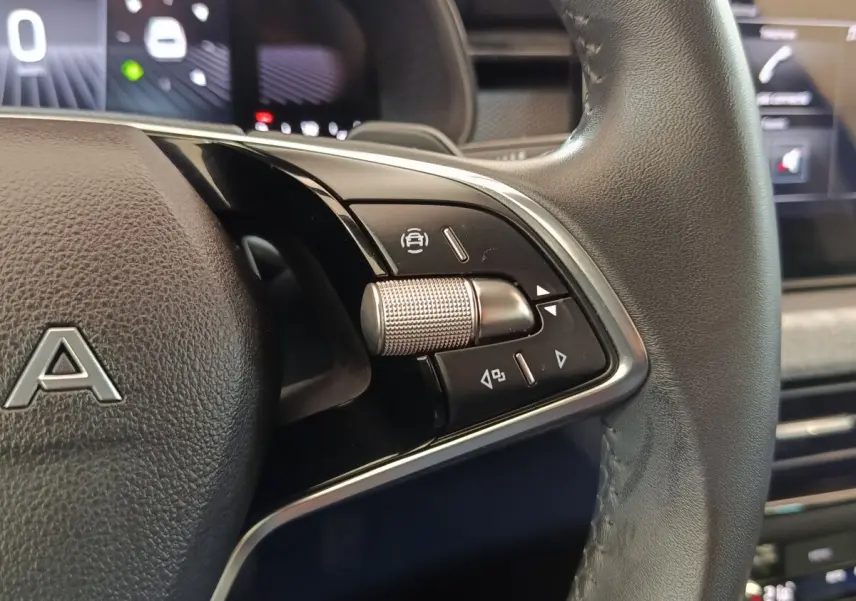 Gros plan sur la commande multifonction droite du volant cuir noir de la Skoda Scala bleu, avec molette métallique texturée.
