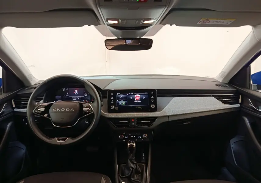 Vue intérieure avant du tableau de bord gris clair et noir du Skoda Scala bleu avec écran tactile central et volant multifonctions.