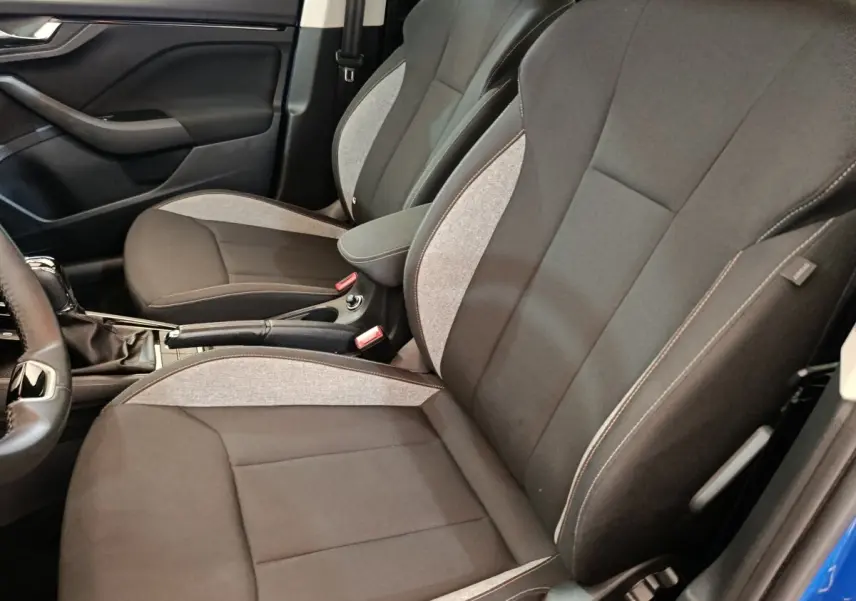Vue intérieure côté gauche des sièges avant gris et noir de la Skoda Scala 1.0 TSI 2025 avec accoudoir central.
