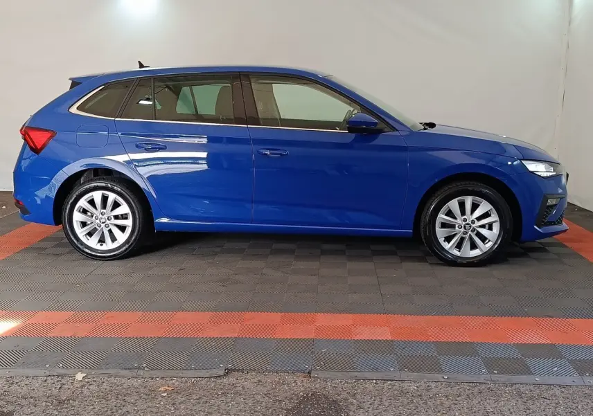 Vue latérale droite d'une Skoda Scala bleu 2025 avec jantes alliage et phares LED allumés dans un studio.