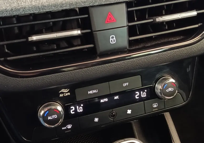 Gros plan sur la console centrale noire du Skoda Scala 2025, avec commandes de climatisation digitale affichant 21°C.