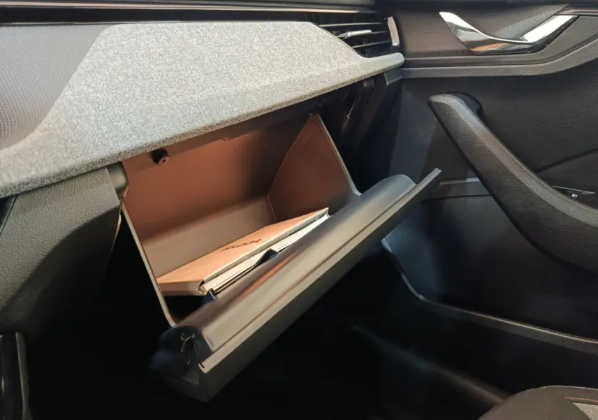 Vue intérieure côté passager du coffre à gants ouvert d'une Skoda Scala 2025 bleu, avec documents visibles à l'intérieur.