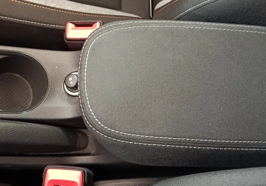 Vue rapprochée de l'accoudoir central noir avec surpiqûres blanches et prise 12V visible sur la Skoda Scala 2025.