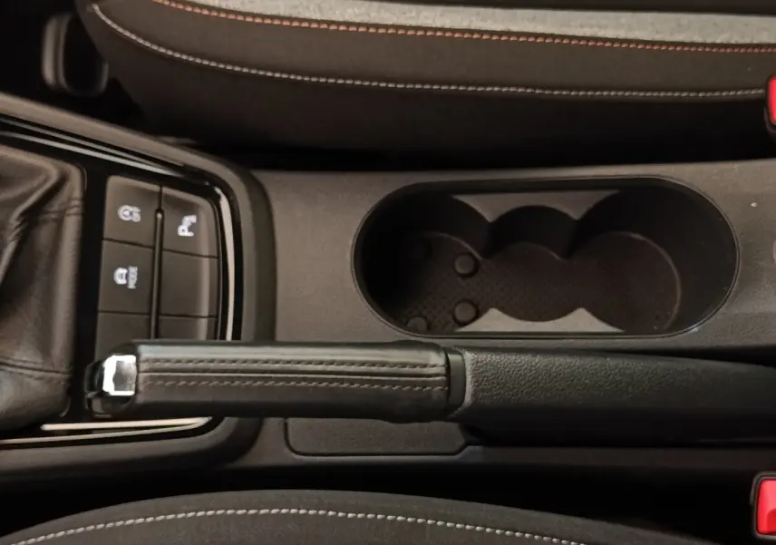 Vue plongeante sur la console centrale de la Skoda Scala 2025, frein à main cuir et porte-gobelets noirs.