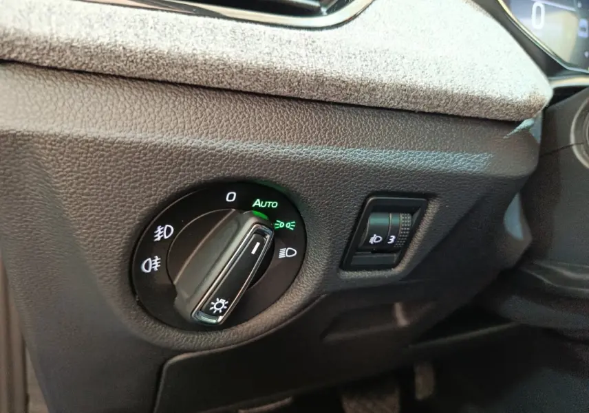 Gros plan sur la commande des phares avec réglage automatique dans l’habitacle du Skoda Scala bleu 2025.