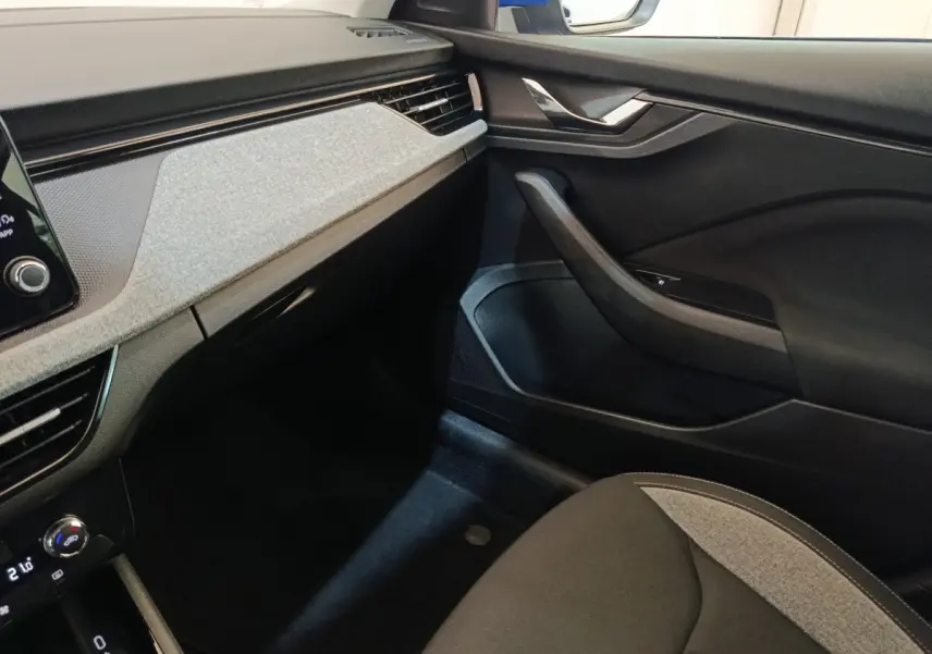 Intérieur avant droit du Skoda Scala 2025, tableau de bord gris clair avec détails noirs et siège tissu bicolore.