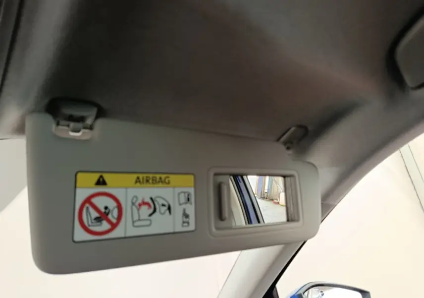 Détail du pare-soleil côté conducteur avec miroir, montrant un reflet du rétroviseur extérieur bleu de la Skoda Scala.