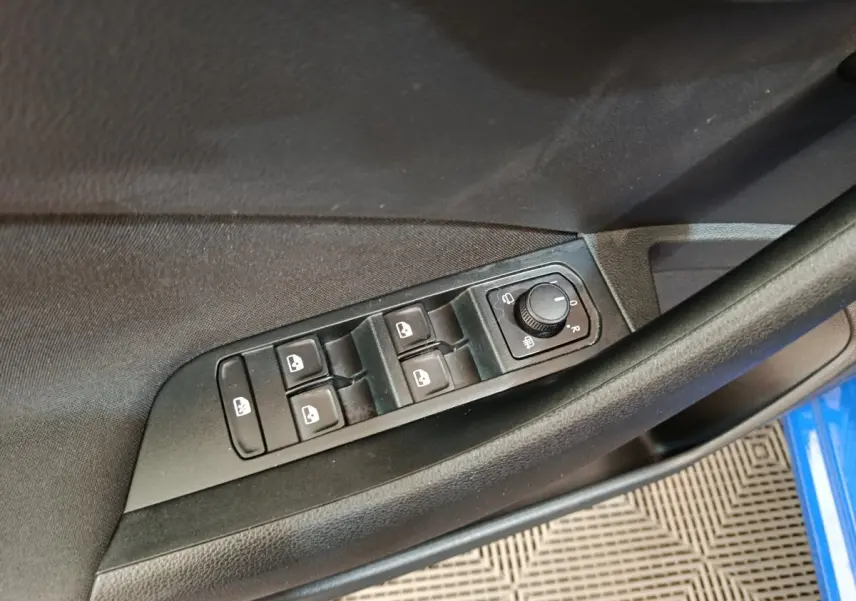 Vue rapprochée des commandes de lève-vitres et réglage des rétroviseurs sur la porte côté gauche d’une Skoda Scala bleue.