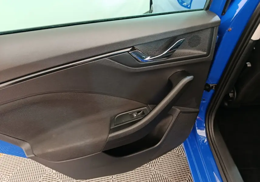 Vue intérieure de la porte arrière gauche d'une Skoda Scala bleu 2025 avec poignée et commande de vitre noire.