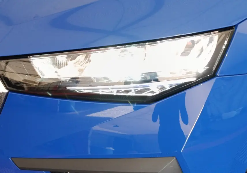 Gros plan sur le phare avant droit d'une Skoda Scala bleu électrique avec lignes anguleuses et finition brillante.