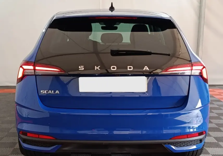 Vue arrière d'une Skoda Scala bleue 2025 avec feux LED et logo SKODA lumineux sur hayon noir.