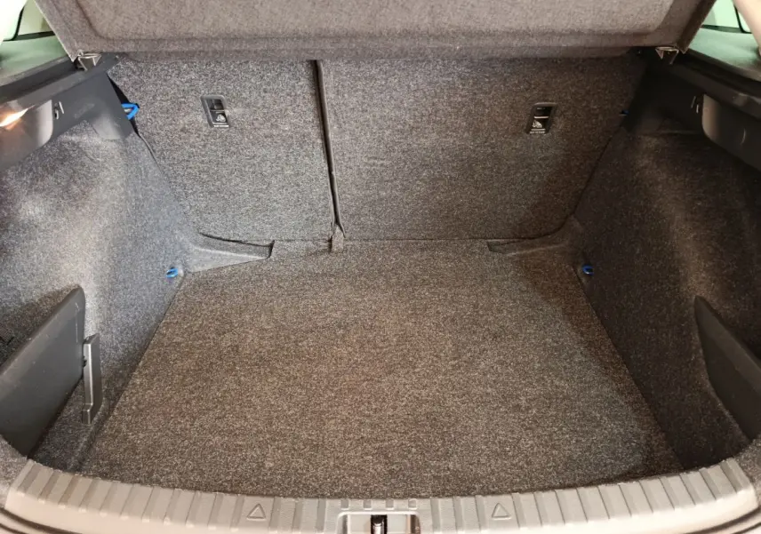 Coffre ouvert vu de face d'une Skoda Scala 1.0 TSI bleu, montrant un espace de chargement tapissé gris.