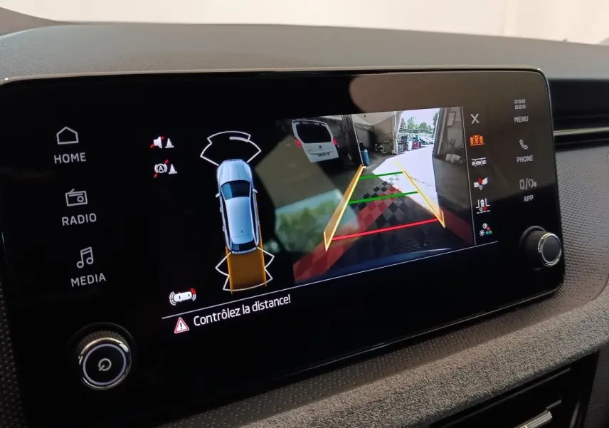 Écran tactile central du Skoda Scala bleu 2025 montrant la caméra de recul avec guidage de trajectoire.