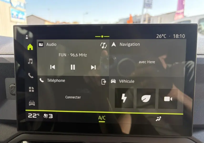Écran tactile central du Dacia Duster 2024 affichant radio, navigation et climatisation en intérieur noir.