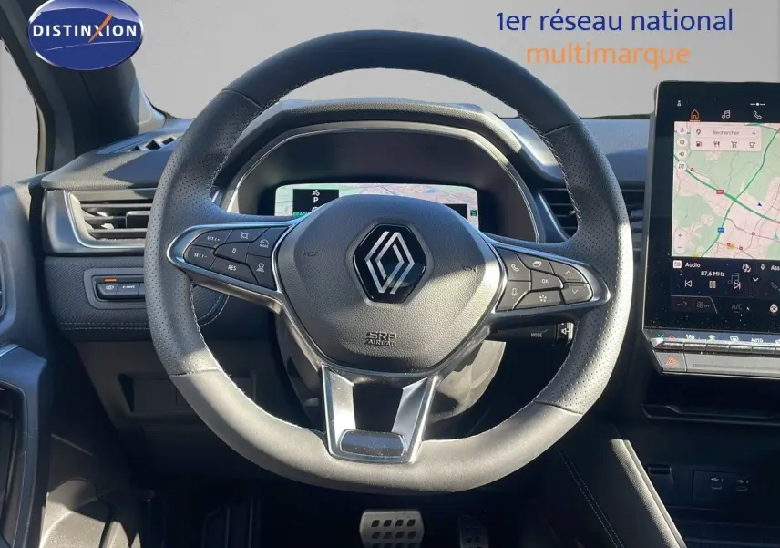 Vue rapprochée du volant en cuir perforé de la Renault Captur E-Tech hybride avec tableau de bord numérique et écran tactile GPS.