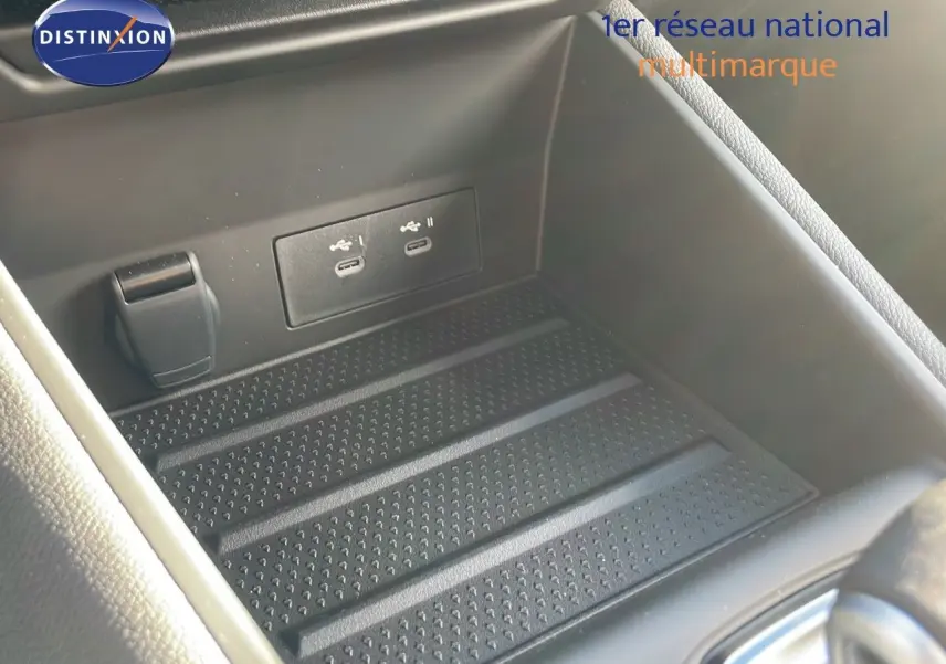 Gros plan sur la console centrale du Renault Captur E-Tech hybride avec ports USB et prise 12V dans un intérieur noir.