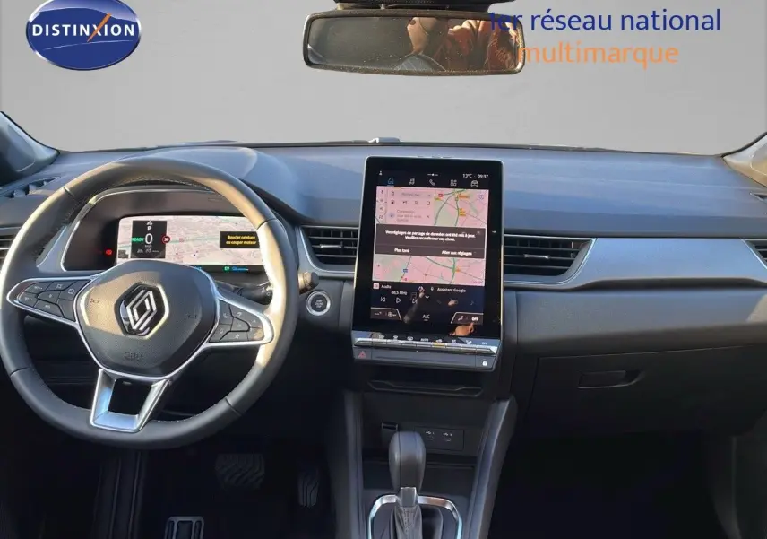 Vue intérieure frontale du tableau de bord du Renault Captur E-Tech Hybrid avec écran tactile vertical et volant multifonction.
