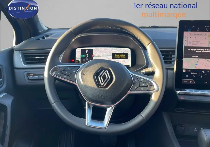 Vue rapprochée du volant cuir noir du Renault Captur E-Tech Hybrid avec tableau de bord numérique et écran tactile central.