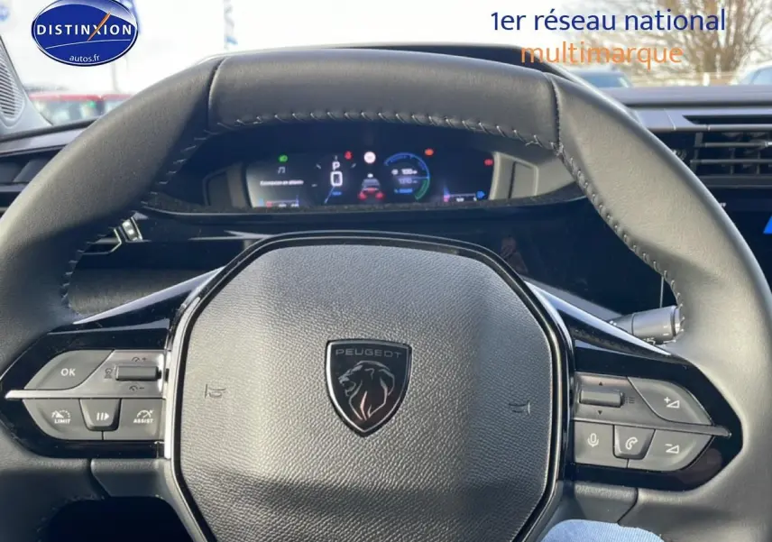 Vue rapprochée du volant multifonction noir de la Peugeot 308 1.2 hybrid 145 allure e-dcs6 avec tableau de bord numérique en arrière-plan.