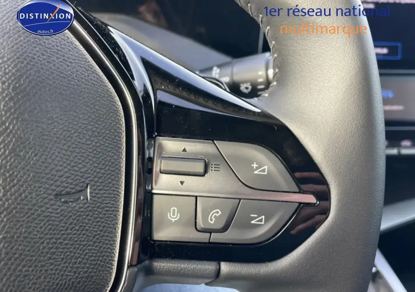 Gros plan sur les commandes multifonctions du volant cuir noir de la Peugeot 308 gris Artense, version 2025.