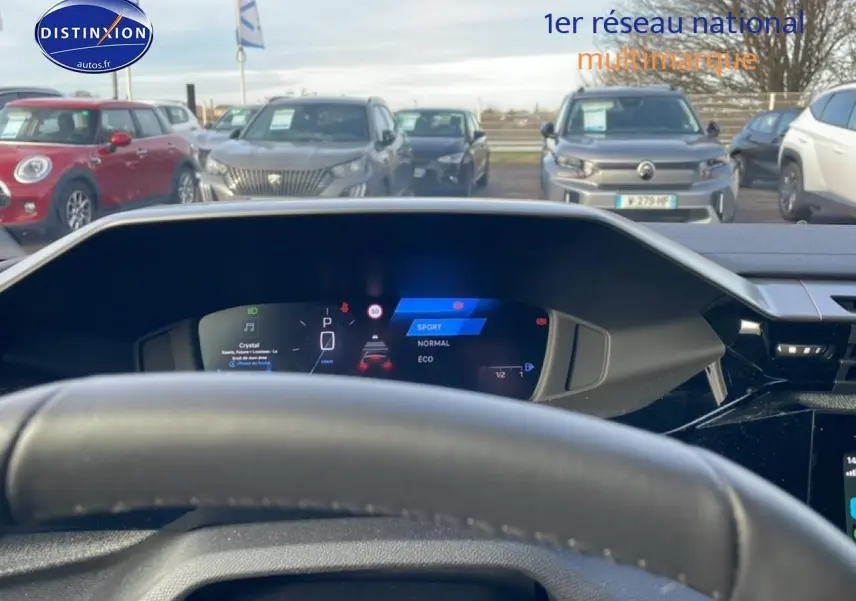 Vue depuis l'intérieur sur le tableau de bord numérique et le volant d'une Peugeot 308 gris artense, avec affichage mode de conduite.