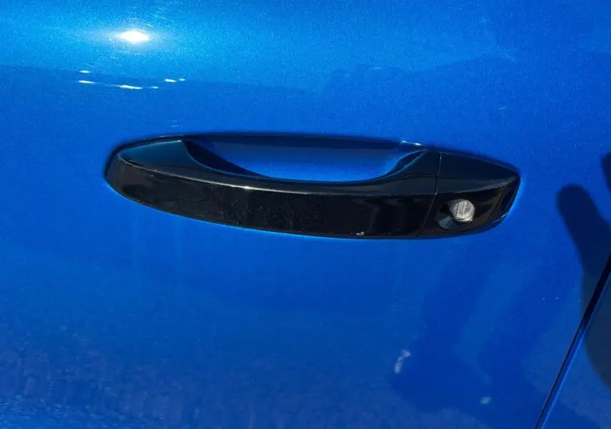 Poignée de porte noire sur la porte avant gauche d'une Citroën C3 bleu vif 2025, vue rapprochée.