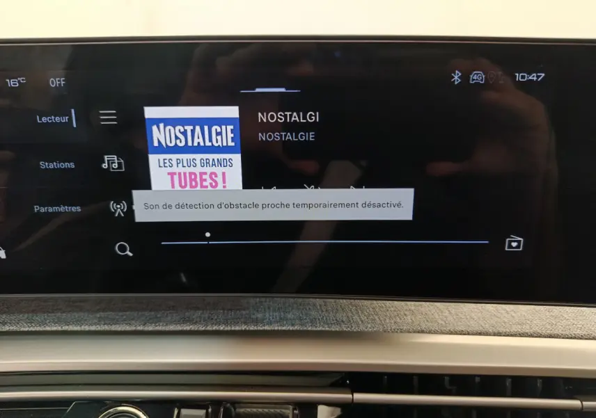 Écran tactile central du Peugeot 3008 gris clair, affichant la radio Nostalgie avec interface moderne.