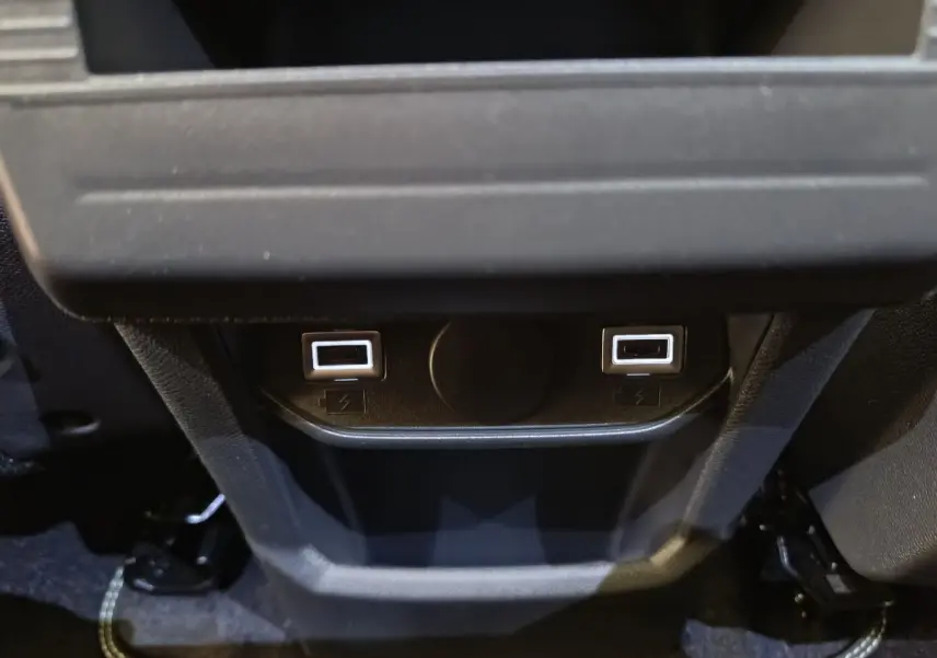 Gros plan sur les ports USB arrière illuminés du Peugeot 3008 gris clair, version hybride 2025.