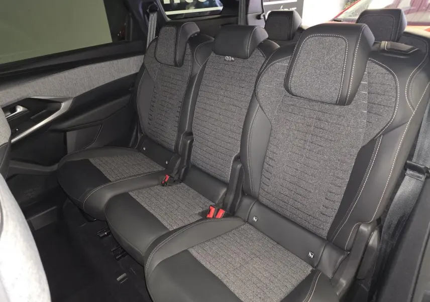 Vue intérieure côté gauche des sièges arrière en tissu gris et cuir noir du Peugeot 5008 1.2i Hybrid 2025.